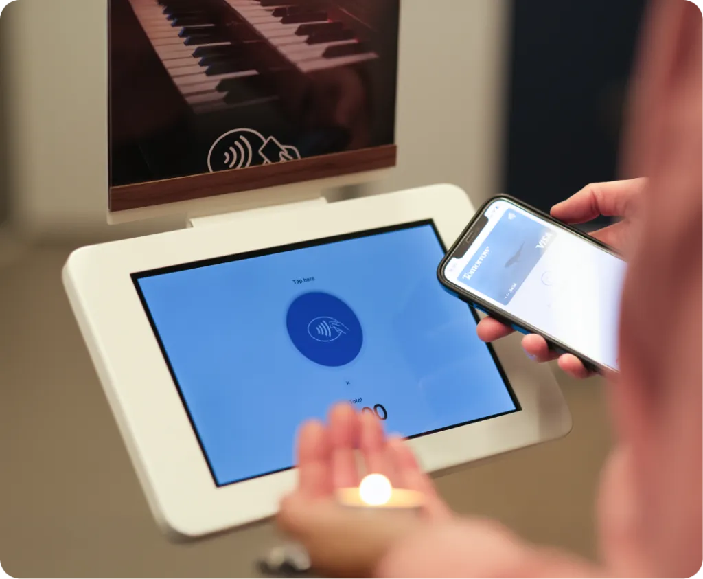 Das ChurchDesk Terminal als Aufsteller mit Kerzen-Poster, während jemand per Smartphone eine Kerzenspende gibt