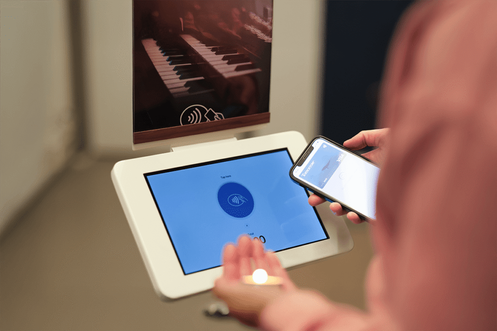 Das ChurchDesk Terminal als Aufsteller, an dem eine Person kontaktlos per Smartphone spendet